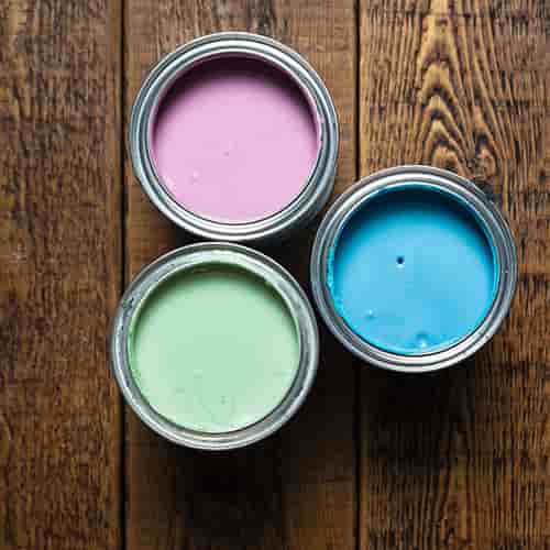 Top view of pastel pink, blue, and green paint in buckets on brown wooden floor