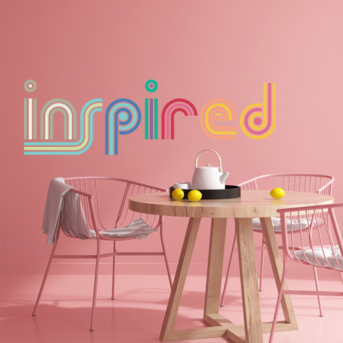 Pink wall and floor with pink metal chairs, wooden table with white tea set and lemons on top, and colored stylized "inspired" text on image